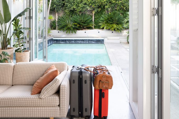 Sofa and packed suitcases inside in front of swimming pool