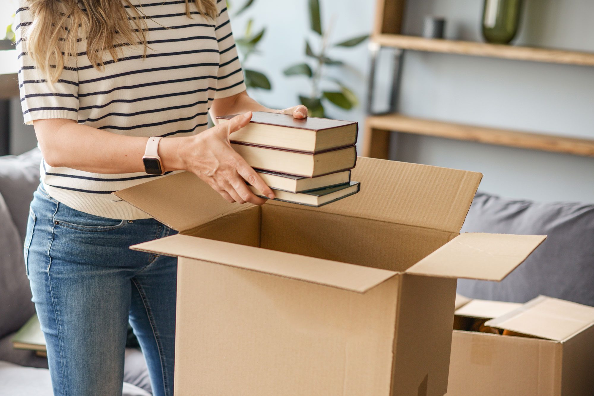 Woman Puts Books In A Cardboard Box