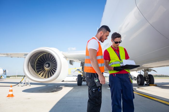 Airport service crew in front of airplane, checking documents