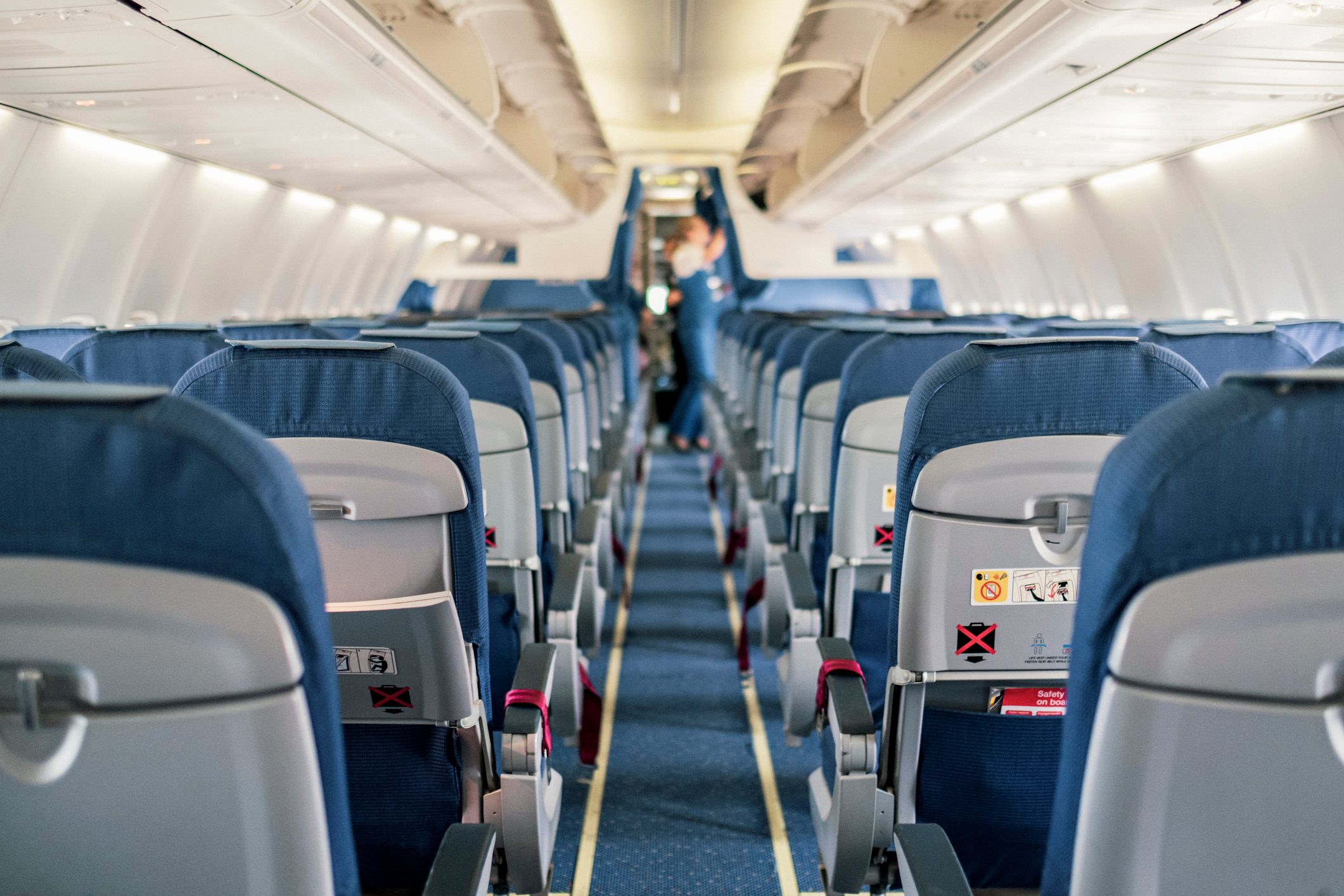 Wide view of an airplane cabin down the aisle facing forward, with three seats on either side