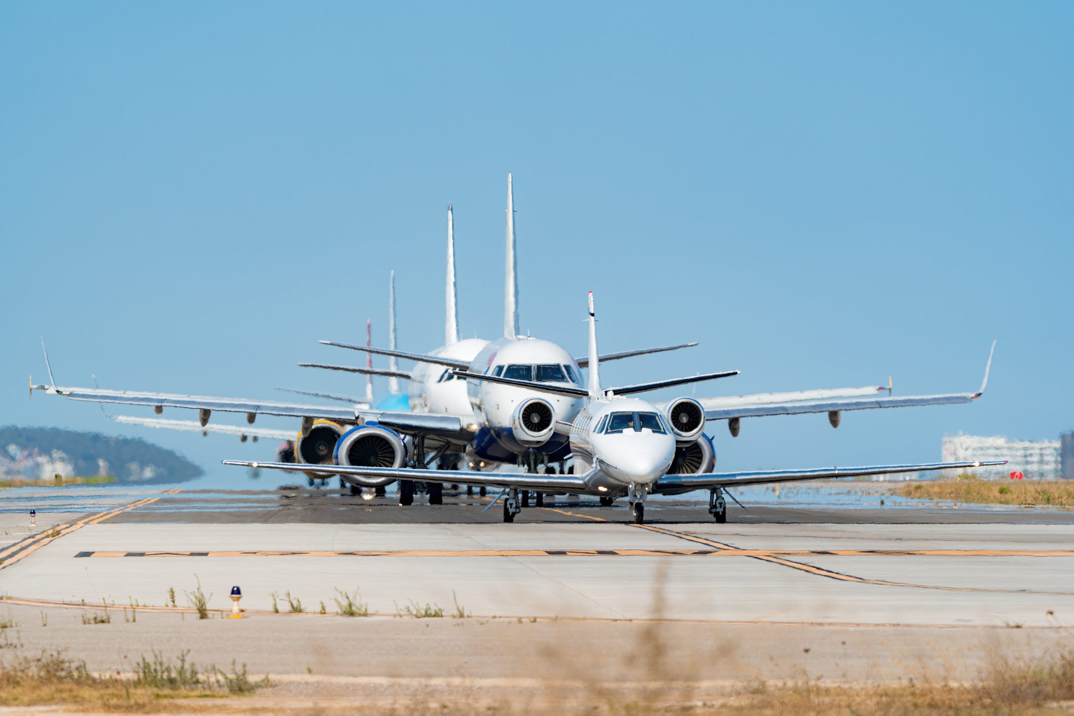 Queue of planes waiting to take off on a tarmac at midday