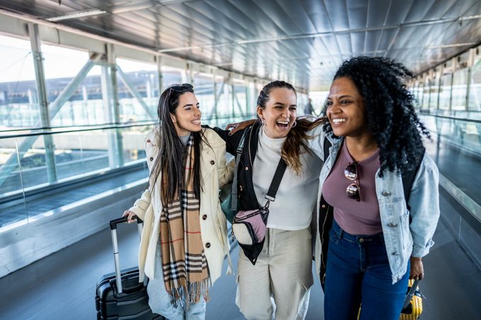 three happy college students walking and talking in a walkway at the airport