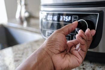 Hand Adjusts Temperature on Kitchen Appliance