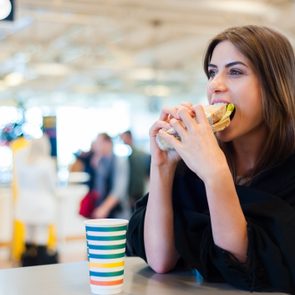 Young woman at airport, drinking expensive coffee and eating a sandwich