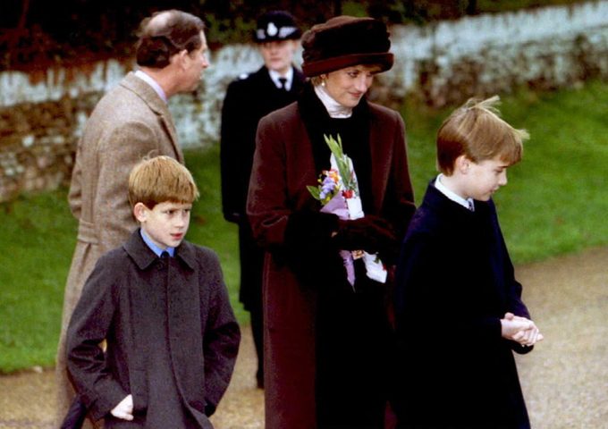 Princess Diana in a maroon coat and hat with her two sons, Prince Harry and Prince William