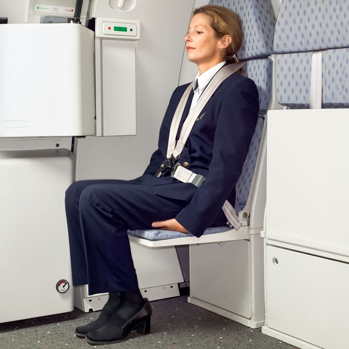 Flight Attendant Sitting On A Jump Seat On Her Hands