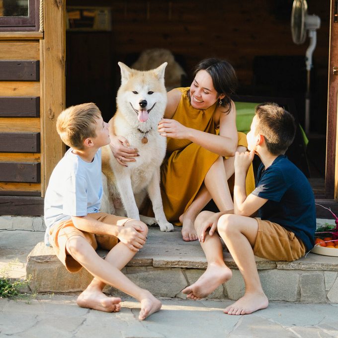 Happy family sitting outside house with Akita dog