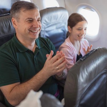 People in airplane seats clapping hands after landing