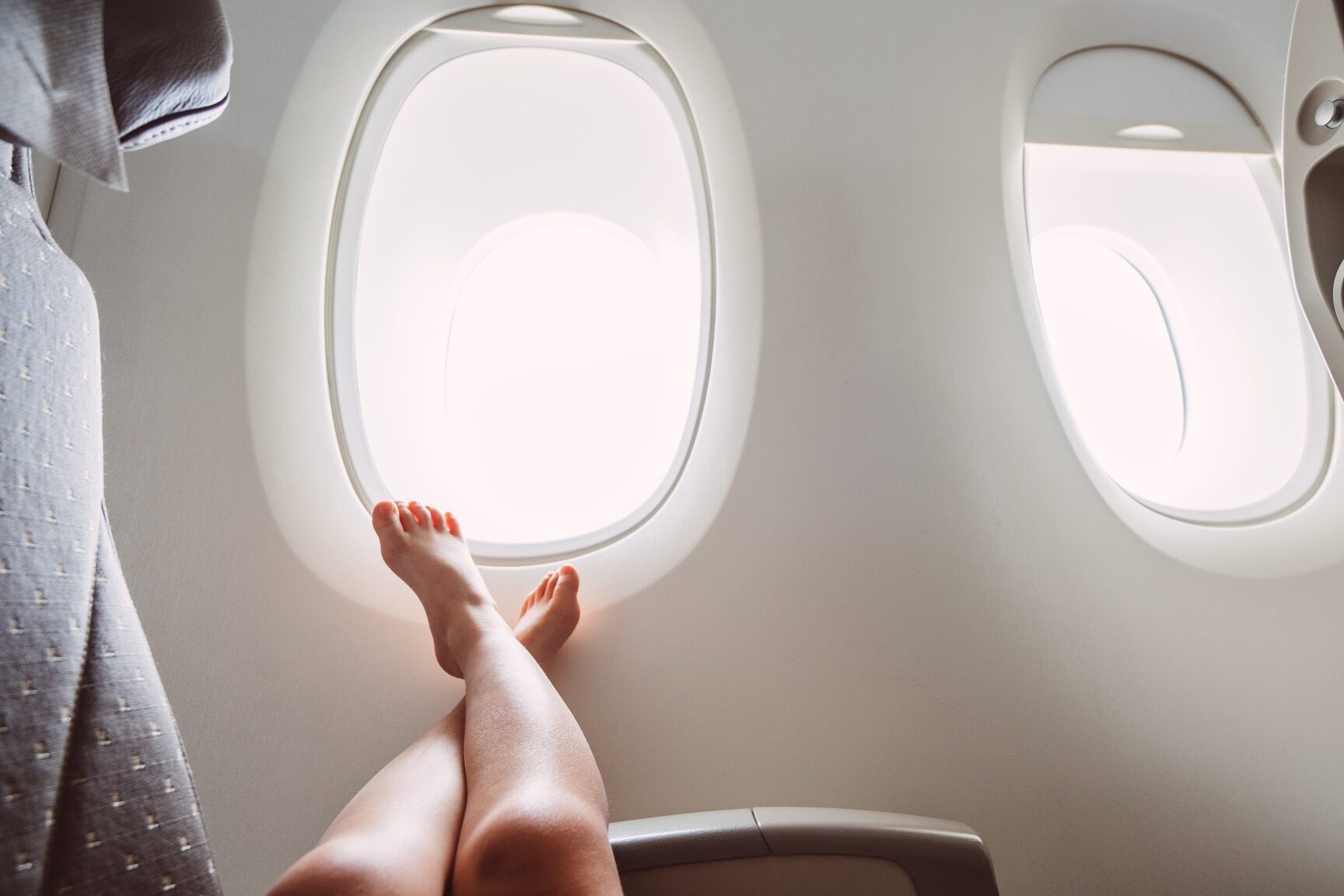 Bare feet up against an airplane window