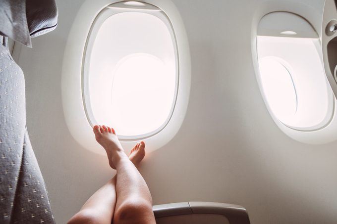 Bare feet up against an airplane window