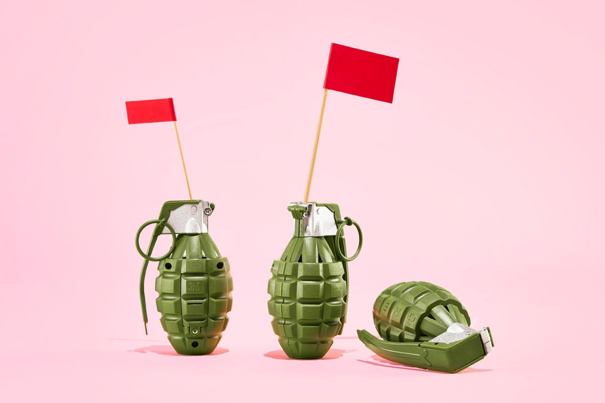 three grenade shaped toys with red flags against a pink background