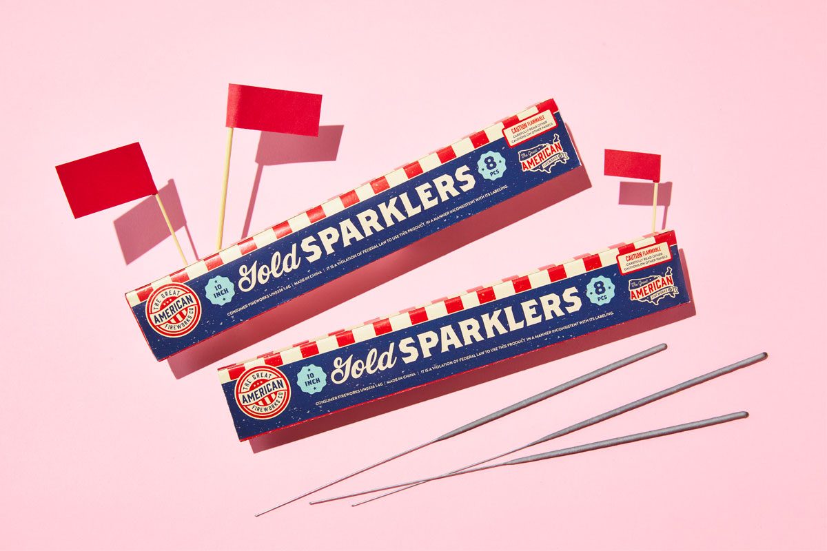 two packages of sprinklers with red flags against a pink background