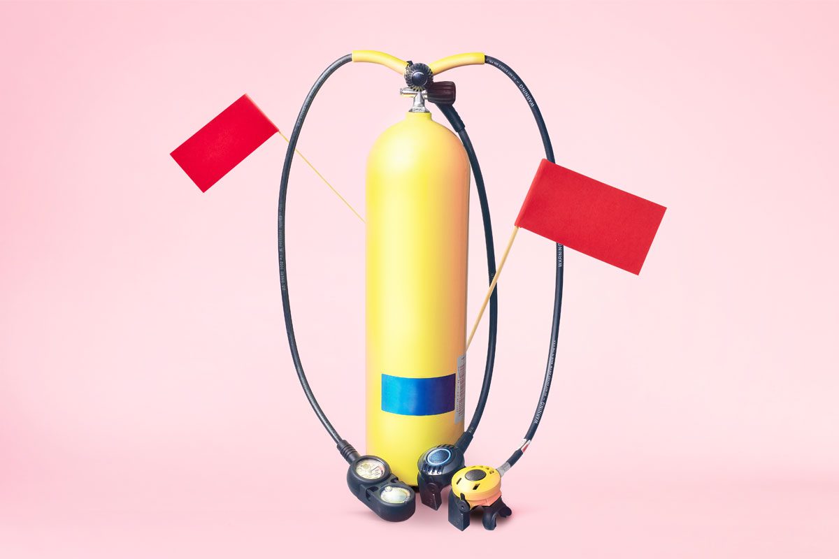 yellow scuba tank with red flags against a pink background