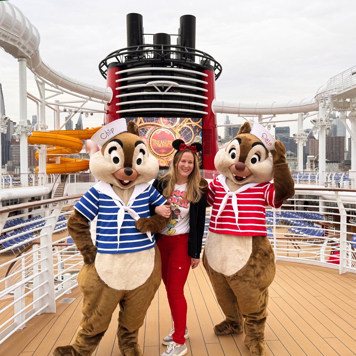 Woman poses for a photo with Chip and Dale chipmunk characters on the deck of a Disney Cruise ship