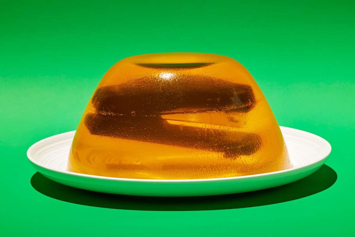 Table view shot of a stapler suspended in yellow Jell-O; preferably in a Bundt cake style mold; green background;