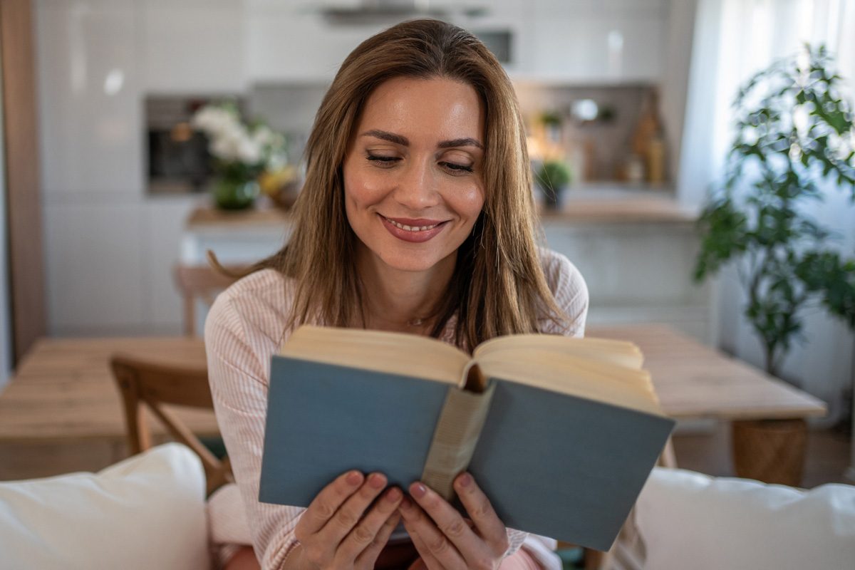 woman smiling while reading a book