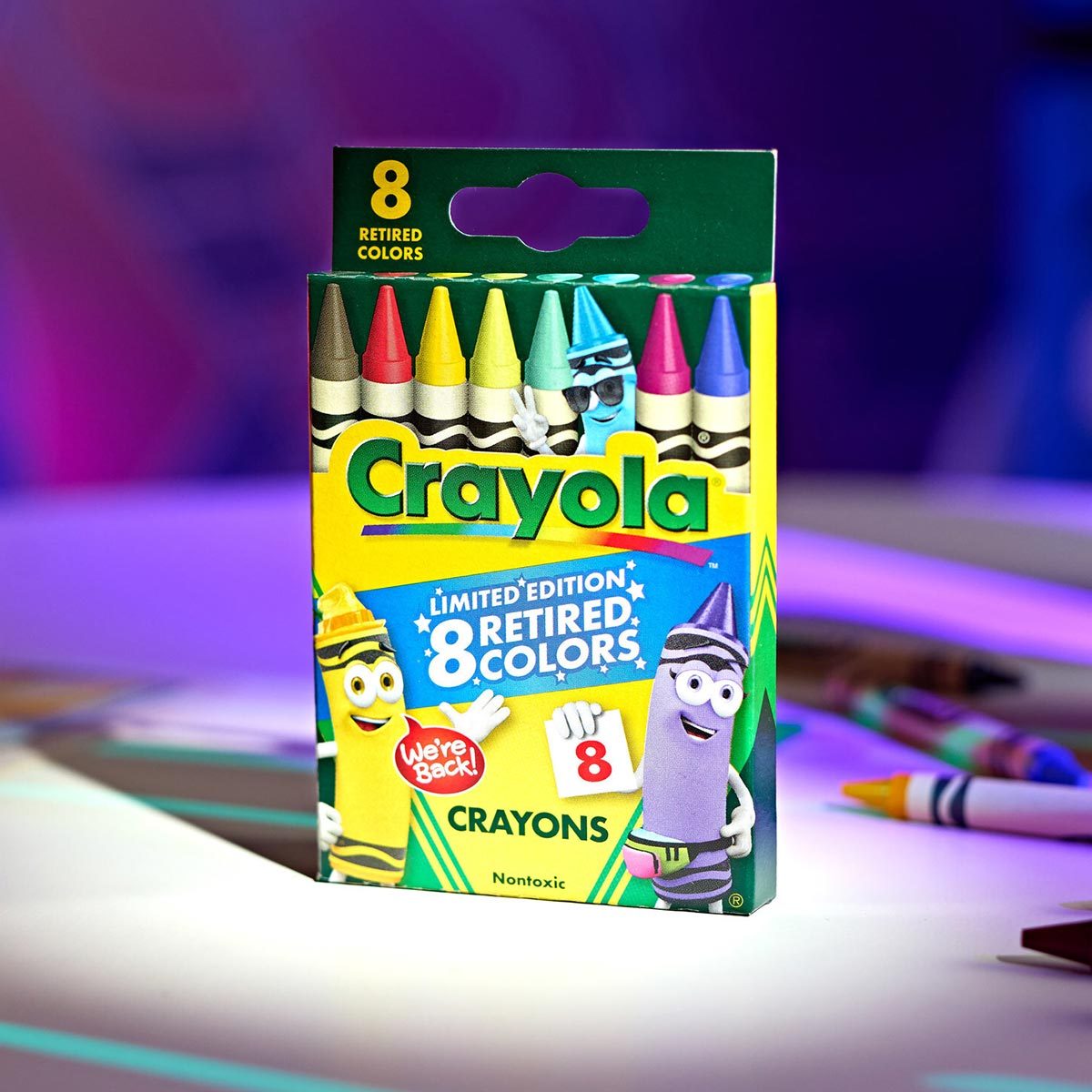 Box of Crayola with eight retired colors with crayons and a purple hue in the background