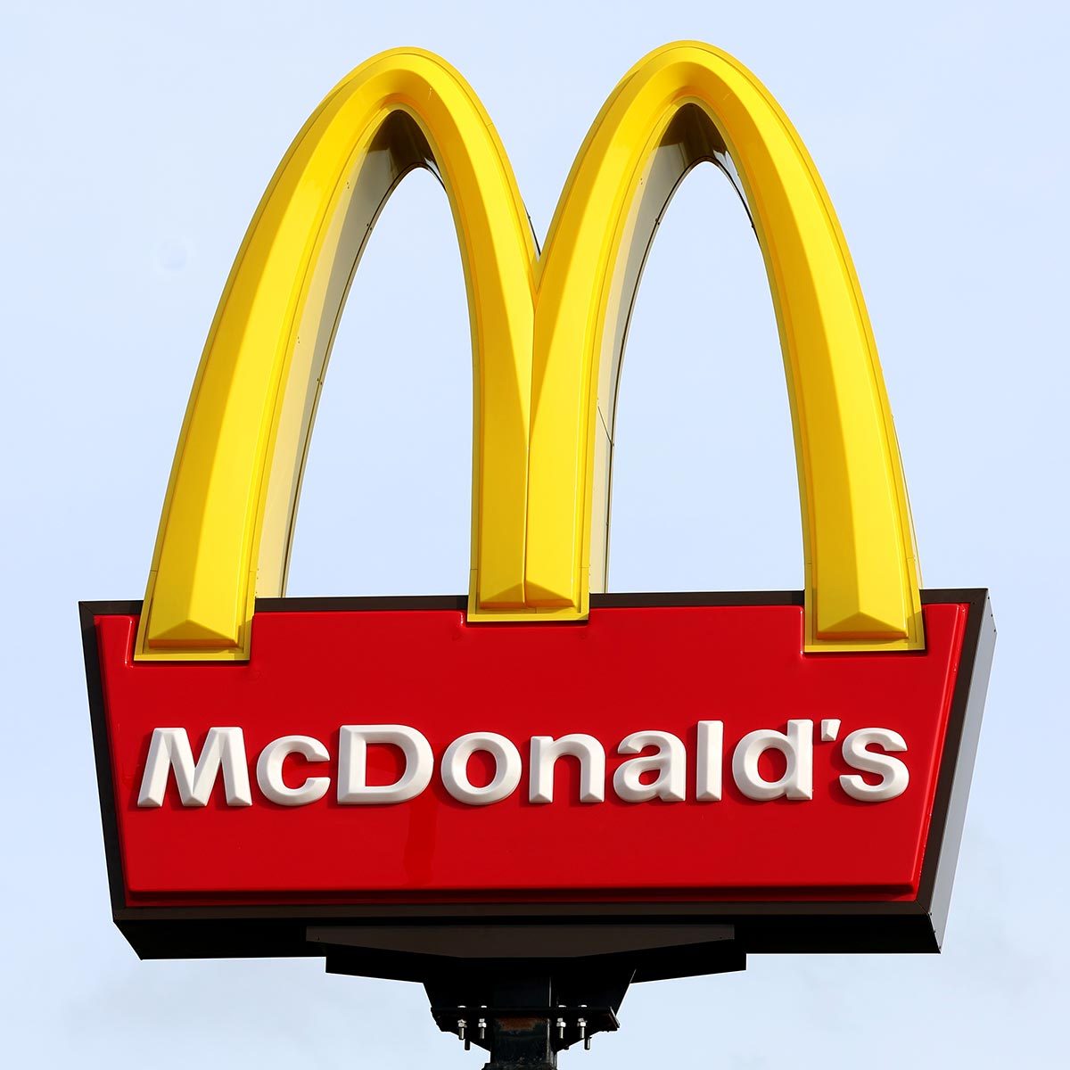 McDonald's sign with golden arches on a light blue sky