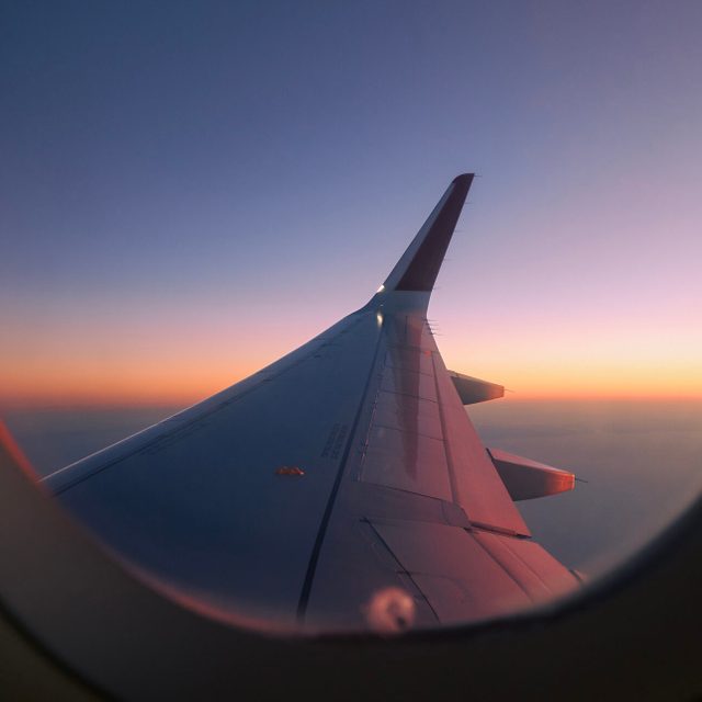 View through airplane window during flight at sunset